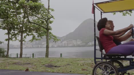 couple riding a pedal quadricycle at lagoa rodrigo de freitas, rio de janeiro