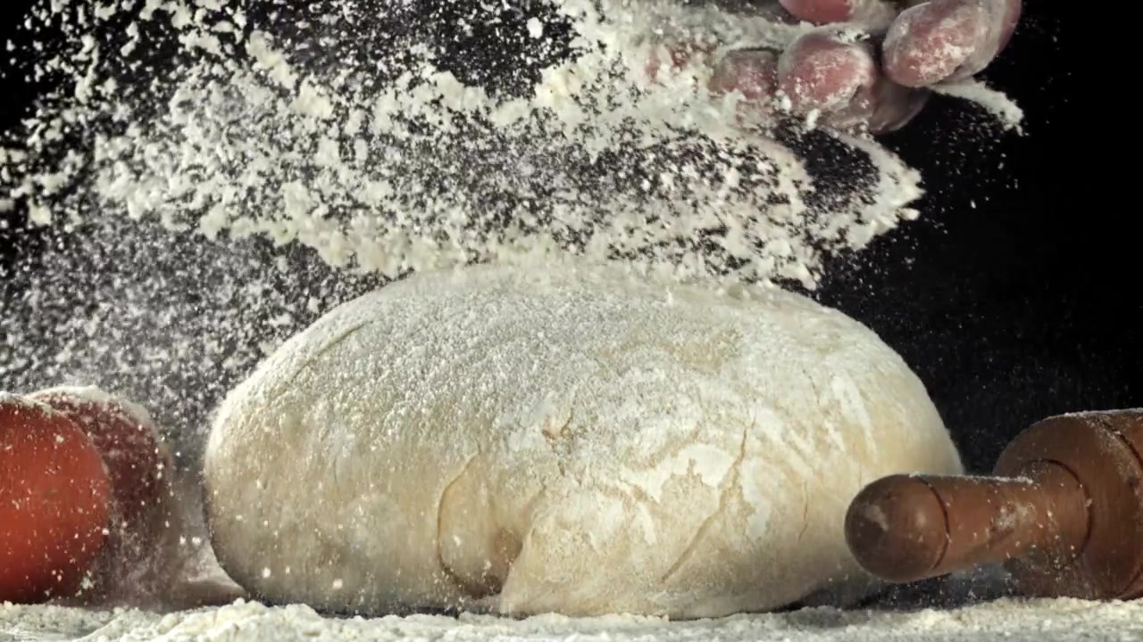 Mani che setacciano la farina sull'impasto fresco al rallentatore