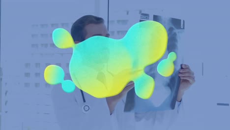 Animation-of-glowing-blob-over-male-doctor-checking-x-ray-scan