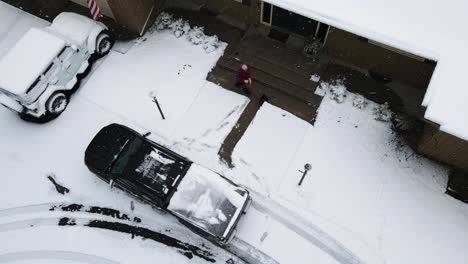 high angel pan with drone of a man shoveling snow