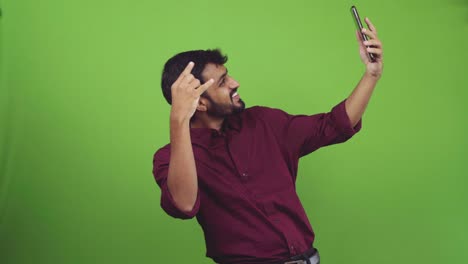 handsome man with beard taking selfies like rockstar, isolated on green screen
