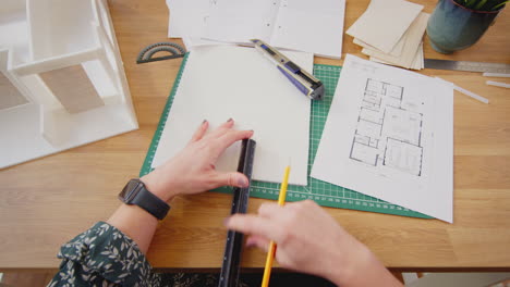 pov filmado con una arquitecta cortando y haciendo un modelo de edificio en el escritorio