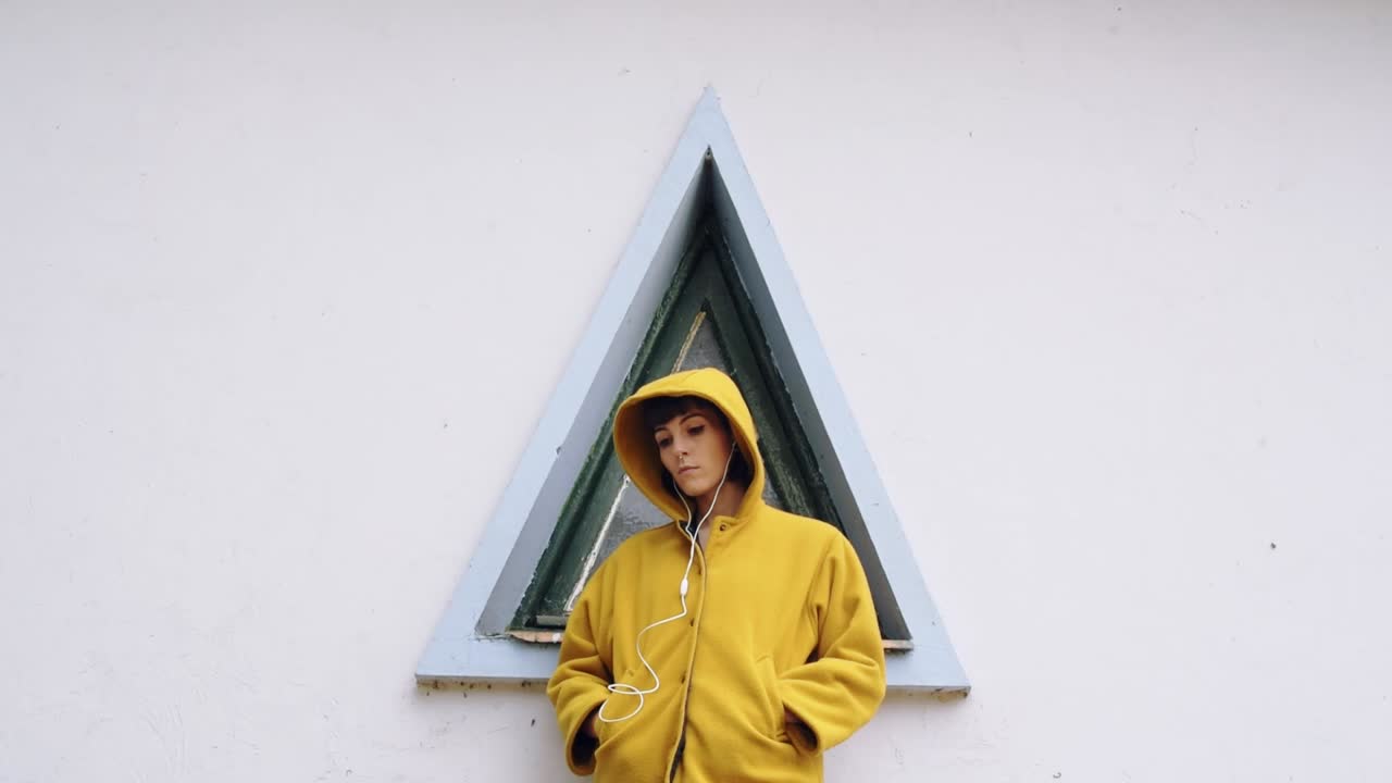 веселая женщина возле треугольного окна слушает музыку