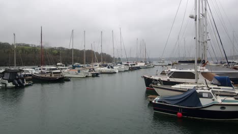 wide shot in the rain of boats yachts moored up on the floating harbour at mylor yacht, churchtown