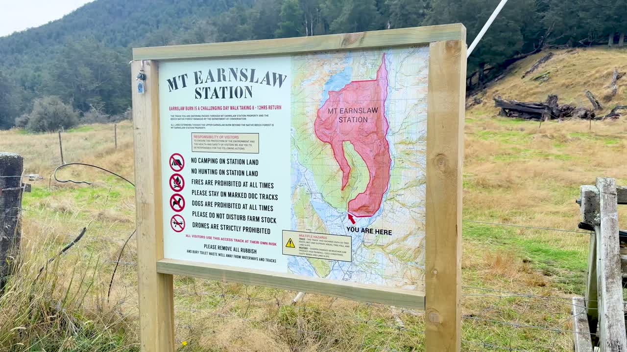 Camera slowly pans across outdoor information sign with map, natural landscape, and soft daylight