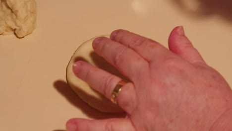 senior woman hands kneading a small piece of raw dough