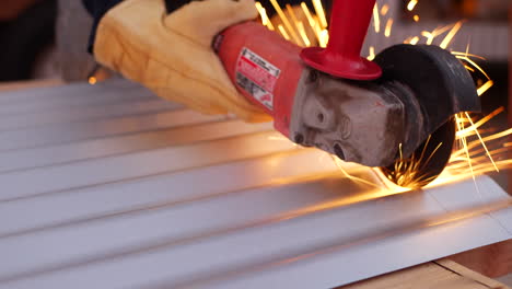 a construction worker using a power tool angle grinder to cut metal and send glowing bright sparks flying in slow motion