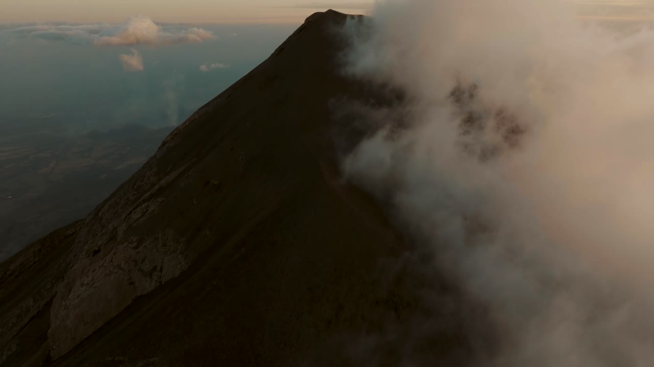 Vulcão Fuego durante o pôr do sol na Guatemala. Elevação aérea.