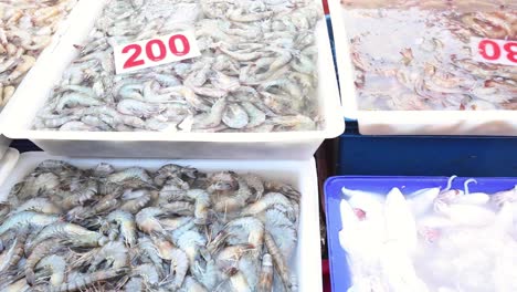 various seafood displayed with price tags at market