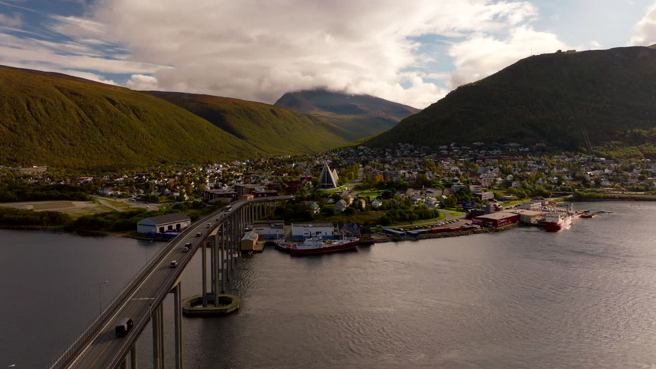 Tromsø Bridge with traffic, and Arctic Cathedral in background, arctic cityscape and mountains in northern Norway in autumn season. Aerial drone