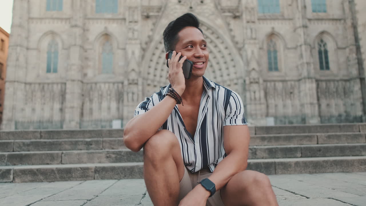 Người đàn ông ngồi trên cầu thang trước nhà thờ lớn đang trò chuyện điện thoại