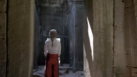 beautiful woman walking through ancient ruins of old stone temple in cambodia