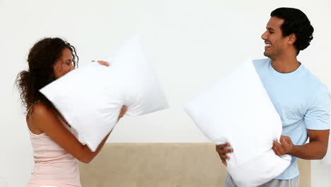 hombre y mujer teniendo una pelea de almohadas