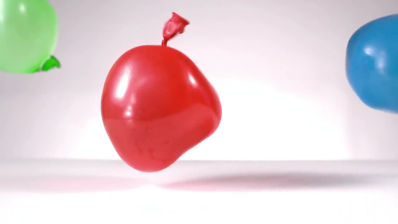 파란색과 초록색과 빨간색의 물 풍선이 떨어지고 있습니다.