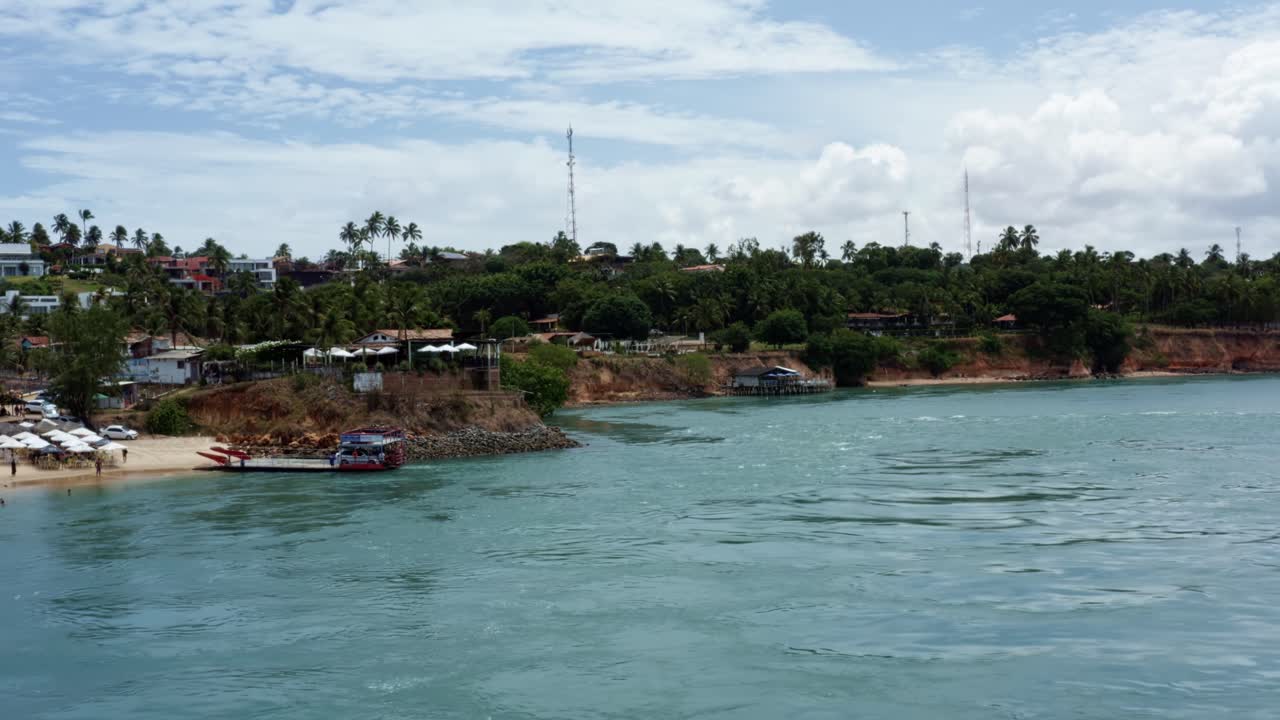 Left trucking aerial drone shot of the tropical cliffs at the famous touristic sunset lookout in Tibau do Sul on the Guara&iacute;ras Lagoon near Pipa, Brazil in Rio Grande do Norte on a warm summer day