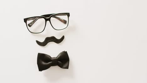 video de bigote falso negro, gafas y pajarita sobre fondo blanco con espacio para copiar