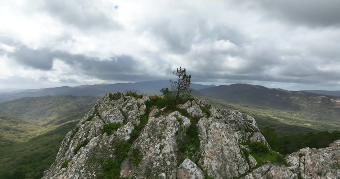 Ripresa aerea ascendente e panoramica di una cima rocciosa vicino a Grazalema, Spagna. Giornata nuvolosa. È visibile un paesaggio montuoso verde con una strada. Filmato ProRes 4K di alta qualità.