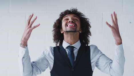 Portrait-Of-Happy-Young-Businessman-Wearing-Suit-Celebrating-Standing-Against-White-Studio-Wall