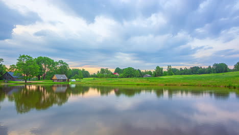 Day-to-blue-hour-purple-glow-sunset-clouds-above-cabin,-reflection-in-lake