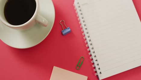 video of notebook, pins and coffee lying on red surface