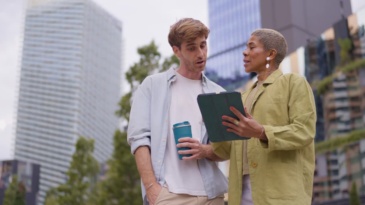 Two people using a tablet while walking in the city