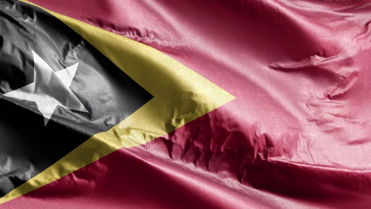 la bandera textil de timor oriental ondeando en el bucle del viento. la bandera de timor oriental balanceándose en la brisa. el tejido textil de la tela. el fondo de relleno completo. bucle de 10 segundos.