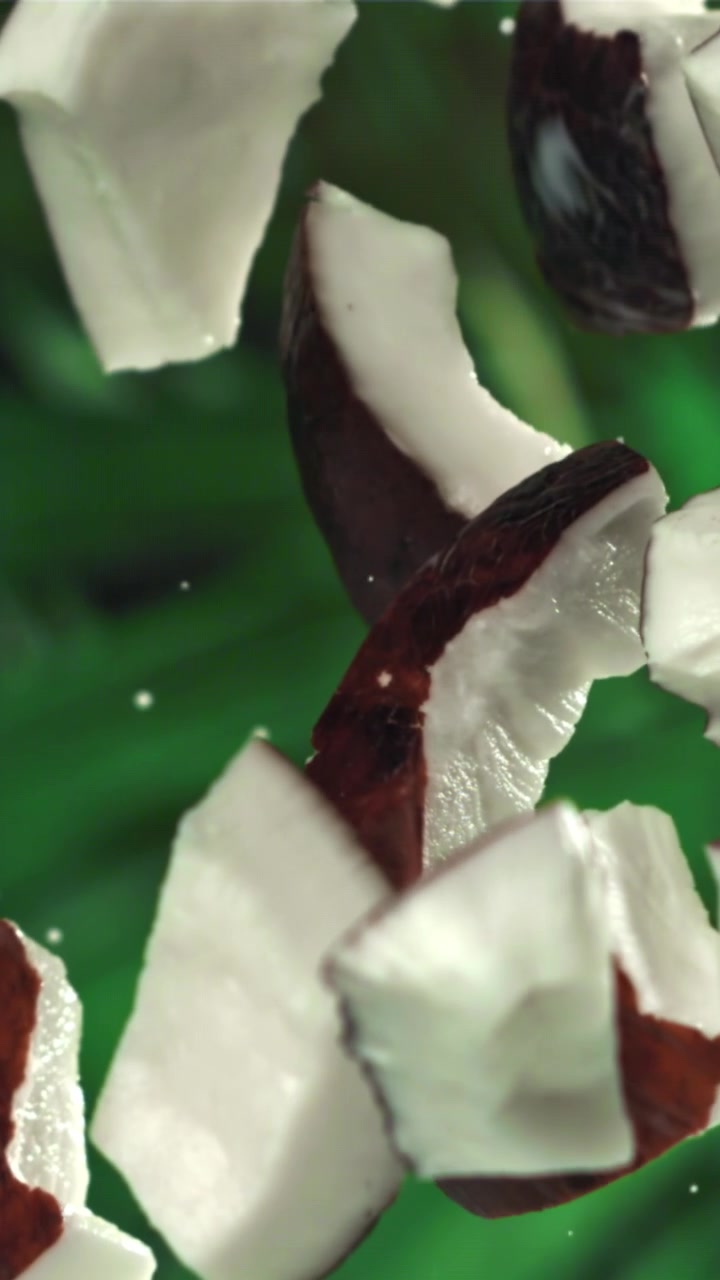 Fresh Coconut Pieces Falling in Slow Motion on Green Background
