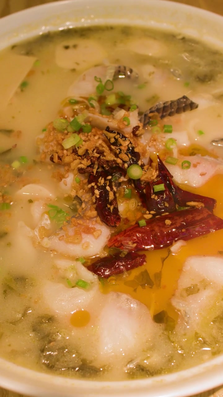 Primo piano di una zuppa di pesce piccante fumante con verdure sottaceto e peperoncini rossi.