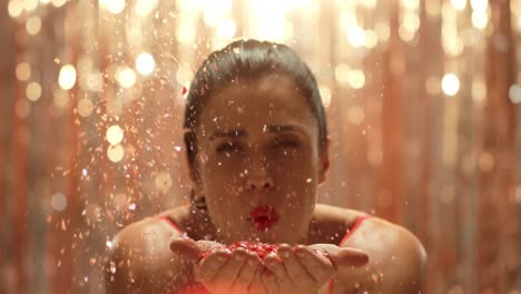 Young-woman-blowing-glitter-to-camera