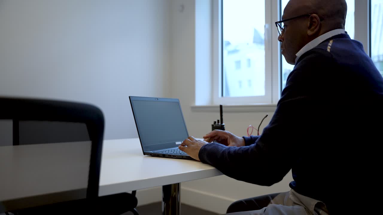 Man working on laptop in bright office setting, focused and productive