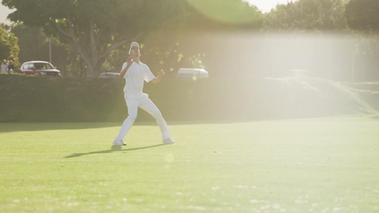 크리켓 선수 가 피치 에서 공 을 잡고 있다
