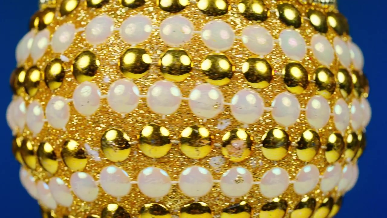 Ornamento di perline scintillante oro e bianco su sfondo blu