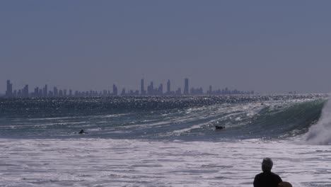 huge waves swashing surfers in the sea. rainbow bay in queensland, australia. wide shot
