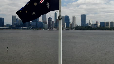 aerial rising shot of the australian flag that reveals perth's impressive cbd skyline and river from sir james mitchell park in south perth