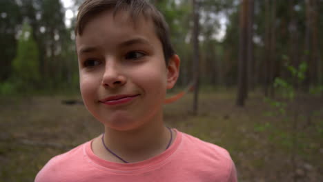 180 degrees portrait of confident teen boy smiling to camera in forest.