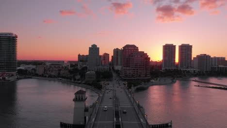 sunset in west palm beach, florida. flying backwards over bridge to the city.