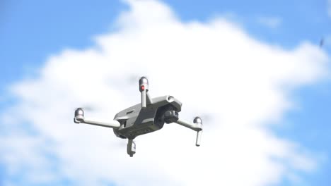 quadcopter drone hovering and flying, blue sky with clouds in the background