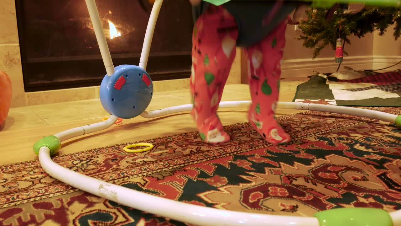 Primo piano delle gambe di una bambina mentre salta eccitata in un girello la mattina di Natale