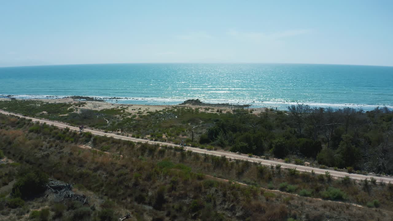 женщина на электровелосипеде, активная и спортивная пенсионерка едет по живописному берегу океана в италии в теплый солнечный летний день