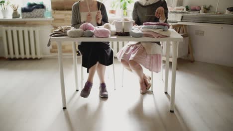 female legs sitting at table and knitting needles. knitting woman