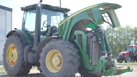 farmer mechanic repairing tractor. open tractor hood, engine. repair agricultural technology