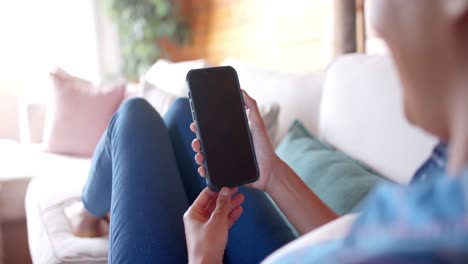 Happy-african-american-woman-using-smartphone-with-copy-space-in-living-room,-in-slow-motion