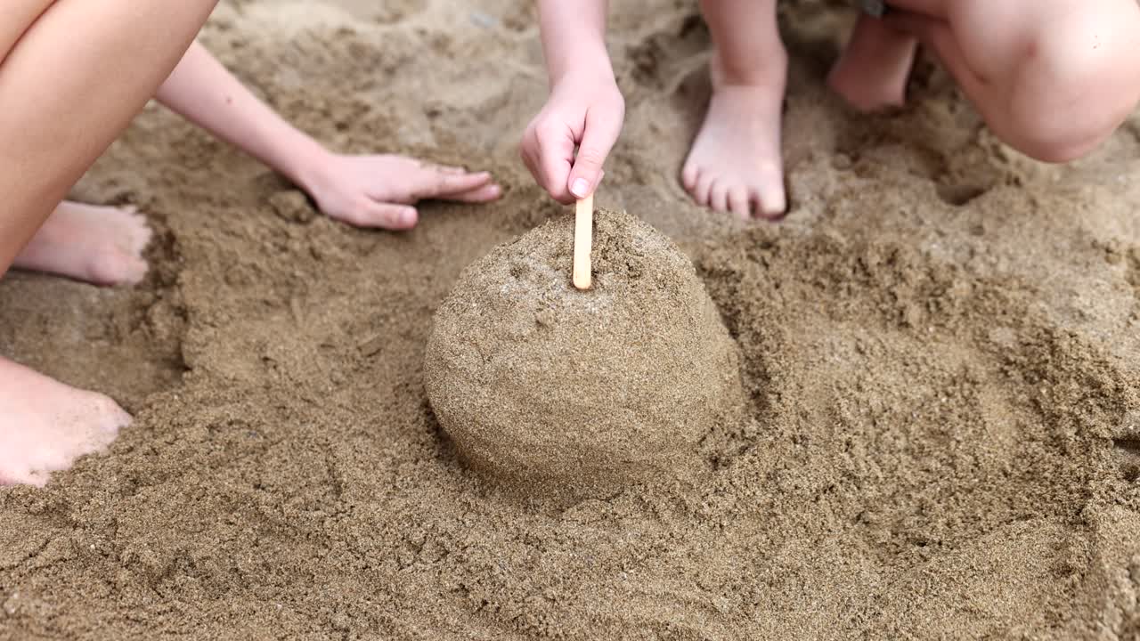 Barnhänder leker och bygger sandslott på stranden på sommaren
