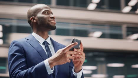 360 degree street shot: portrait of happy black businessman using smartphone in city. smiling african american entrepreneur using mobile phone app stock market investment. tracking moving around shot