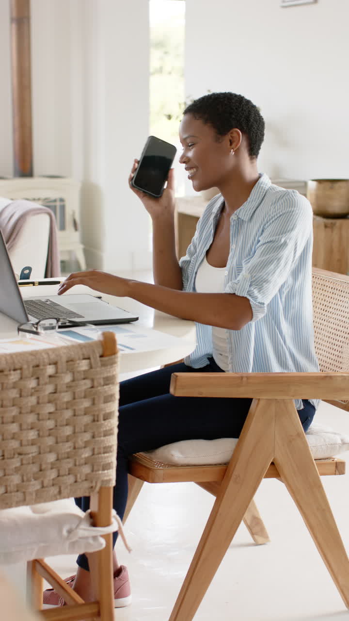 Slow-motion video: African American woman multitasks with laptop and smartphone
