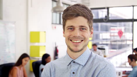 young white man in office walks into focus, and smiles