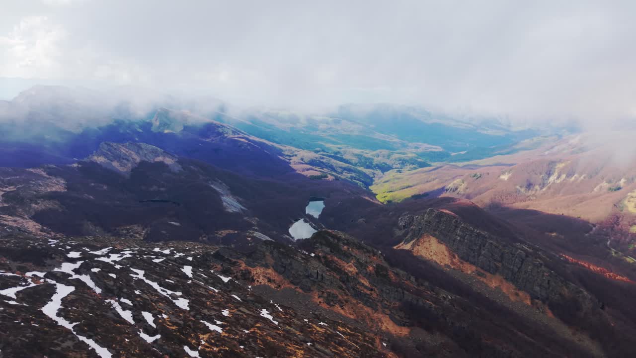 Stunning aerial view of the Dolomites Mountains showcasing rugged terrain, a lake, and distant peaks