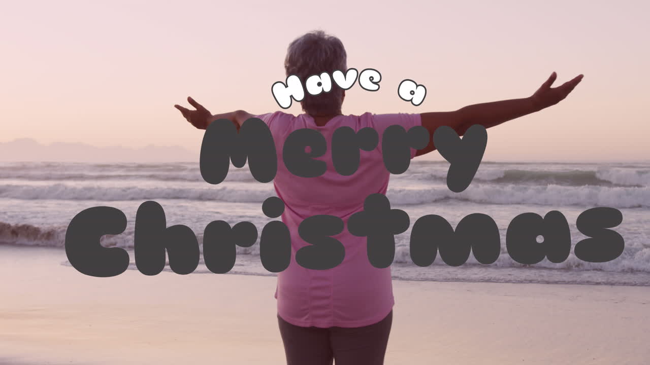 animación de saludos de navidad texto sobre mujer biracial senior en la playa.