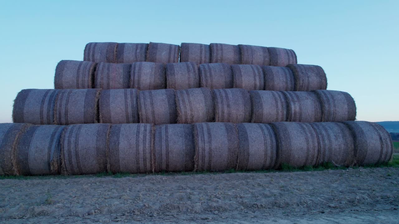 las balas de heno, apiladas en una pirámide, secas en el campo al atardecer.