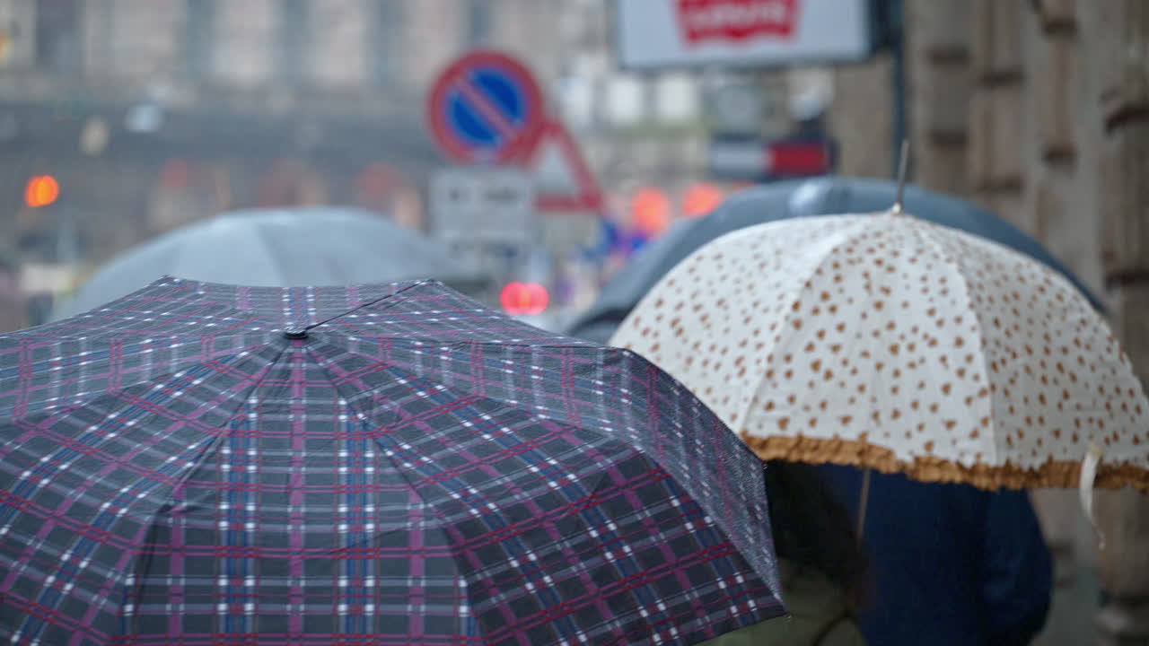 People holding umbrellas walking in the rain on thee street in Milan, Italy